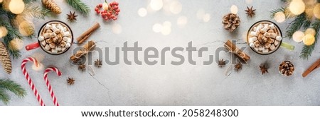 Christmas holiday creative layout with marshmallow hot chocolate, pine tree, red berries, candy canes, and pine cones, cosy Christmas flat lay Royalty-Free Stock Photo #2058248300