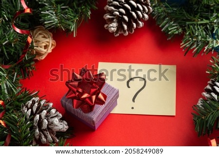 Gift box with a red bow on red background with question sign, Christmas unboxing theme. What to give on a new year.