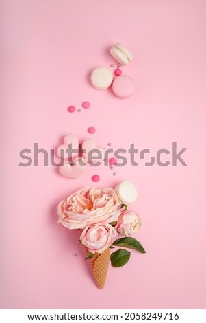 Flat lay of a waffle cone filled with roses and French macarons with heart shaped macarons and pearls, Contemporary food and art picture 