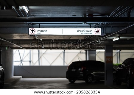 Carparking Lighting box is hung on ceiling. Thai Laungae letter on lighting box at the left side mean "EXIT" and right side mean "No RIGHT TURN".