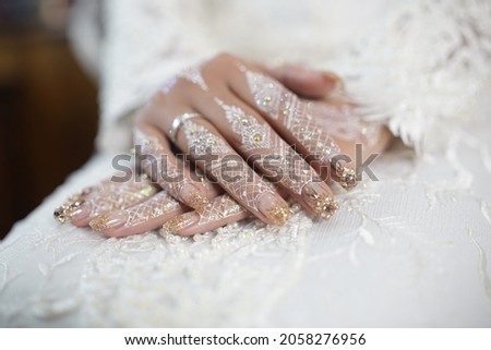 Woman's Hands with white henna art tattoos. Hands of bride girl with mehndi and perfect gold manicure and jewels for the wedding. 