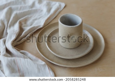 ceramic cup and plates on a wooden table top view. minimalist set of handmade ceramic tableware and pottery Royalty-Free Stock Photo #2058285248