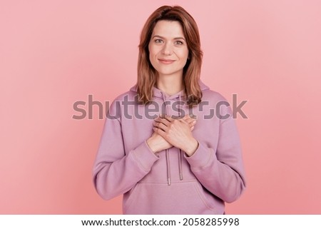 Photo of young cheerful woman happy positive smile hands on heart grateful appreciate isolated pink color background