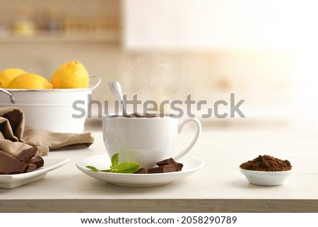 Hot chocolate in white ceramic mug, pieces and chocolate powder in bowl on wooden table white isolated background. Front view. Horizontal composition.