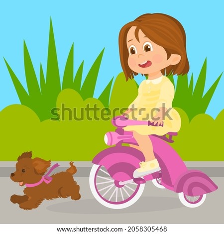 Little girl on bike and puppy running outdoor