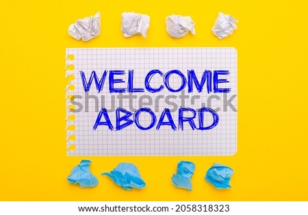 On a yellow background, white and blue crumpled pieces of paper and a notebook with the text WELCOME ABOARD