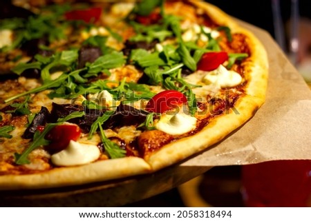 fresh pizza with pieces of meat, tomatoes and herbs with mozzarella cheese close-up