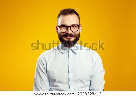 Headshot of satisfied cheerful handsome man grins at camera, glad to find suitable well paid job, isolated over yellow background