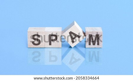 text spam - letters by on woodens blocks on blue background, in concept of business and corporation