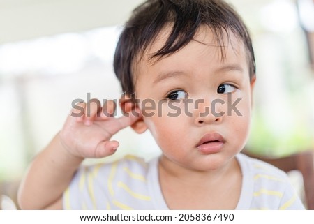 Little asian toddler baby boy has earache when insects inside outdoor baby infant boy hands touching in ear and pain.deaf kid.Flu and sick.Clean up earwax.Accident in kid with ear.Condition and clean. Royalty-Free Stock Photo #2058367490