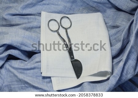 Scissors with an additional area for the convenience of cutting elements lie on a linen scarf in the designer's studio.