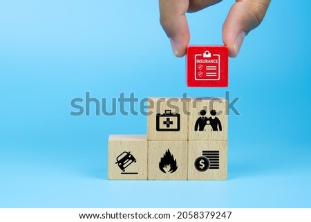 Close-up hand chooses cube wooden toy blocks stacked with insurance prevent and protect icon for safety family health insurance and car accidents prevention and shield concepts.