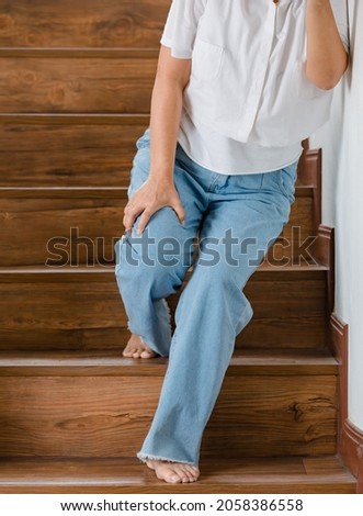 Woman stops for rest and leaning on wall for support while she cannot climb stairs with tingling legs. Concept of Guillain barre syndrome and numb legs disease or vaccine side effect. Royalty-Free Stock Photo #2058386558