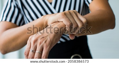 Woman shows hand and hold wrist with feeling pain, suffer, hurt and tingling. Concept of Guillain barre syndrome and numb hands disease effect.
