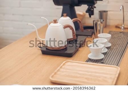 Wooden counter with kettles, coffee cups and tray in cafeteria Royalty-Free Stock Photo #2058396362
