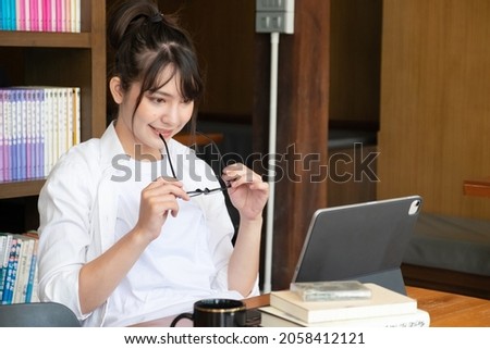 Portrait of young businesswoman with hand touch her glasses and working on computer while sitting at her office desk.

