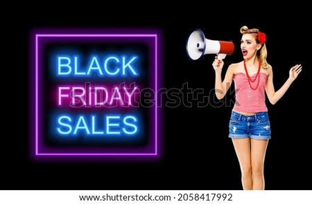 Blond haired woman holding megaphone and shout something. Girl in red pin up style, isolated over dark color background with copy space. Black Friday sales neon light sign. Advertising ad concept. 