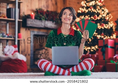 Photo of cute dreamy young woman dressed green costume celebrating new year holding modern gadget letters indoors room home house