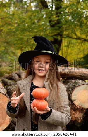 Close up portrait of cute girl with pumpkin in her hands. little girl which celebrate Halloween outdoor and have fun. Kids trick or treating.Happy Halloween or Thanksgiving.Focus on eyes