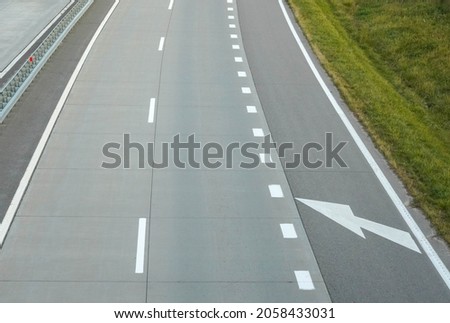 Photo of a gray road with white road markings.