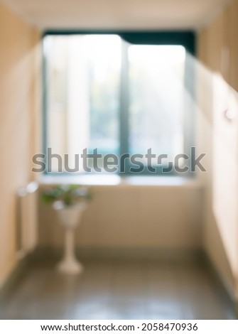 A blurry image of a corridor with a window and a door of an office space
