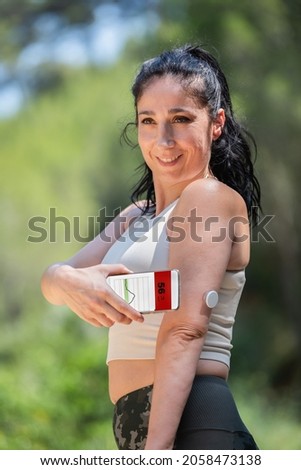  Woman showing glucose monitoring and checking with remote sensor and smartphone Royalty-Free Stock Photo #2058473138