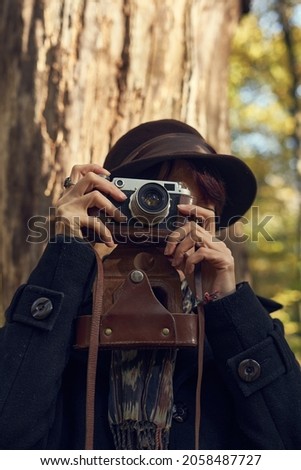 40's old elegant lady using vintage photo camera in the park