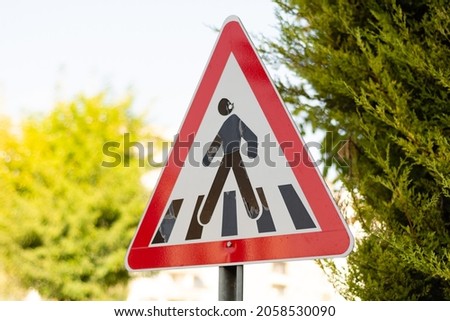 Crossing area traffic sign. Warning for pedestrian crossing. Reminder to obey traffic rules. Red road sign. Roadside information symbols. Pedestrian safety.