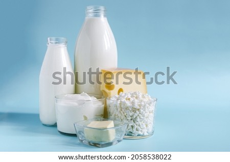 Dairy products in close - up in transparent dishes on a blue background . Milk, kefir, sour cream, cheese, butter and cottage cheese in a glass container on a light background Royalty-Free Stock Photo #2058538022