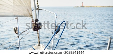 White sloop rigged yacht sailing in the open sea on a clear day. A view from the deck to the bow. Dolphin close-up. Transportation, travel, cruise, recreation, leisure activity, wildlife photography