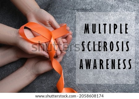 Multiple Sclerosis Awareness Day. People with orange ribbon on grey background, top view Royalty-Free Stock Photo #2058608174