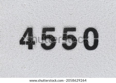 Black Number 4550 on the white wall. Spray paint. Number four thousand five hundred fifty.