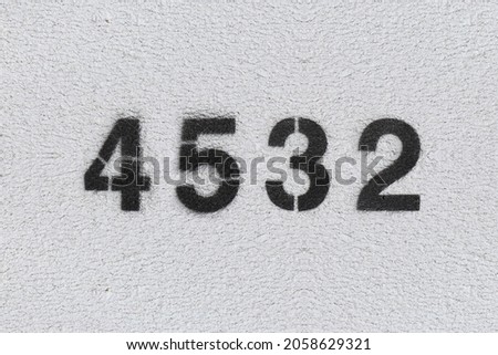 Black Number 4532 on the white wall. Spray paint. Number four thousand five hundred thirty two.