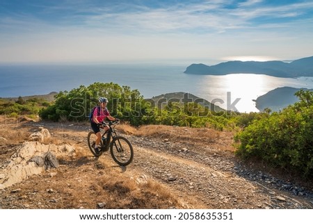 nice woman riding her electric mountain bike during sunset on the coastline above the mediterranean sea on the Island of Elba in the tuscan Archipelago, Tuscany, Italy Royalty-Free Stock Photo #2058635351
