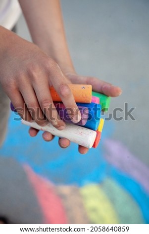 Chalks. Large multi-colored crayons in children's hands. The child holds the chalk. Draw on the street. Fascinating drawing for children