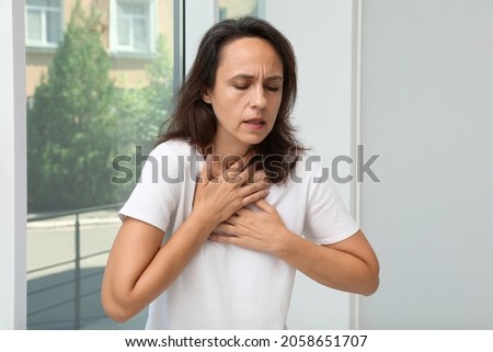 Mature woman suffering from breathing problem near window indoors Royalty-Free Stock Photo #2058651707