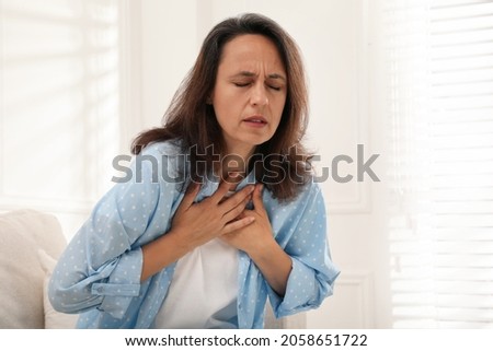 Mature woman suffering from breathing problem at home Royalty-Free Stock Photo #2058651722