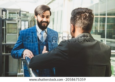 young business people are standing and talking on the background of glass offices. Corporate businessteam and manager in a meeting.