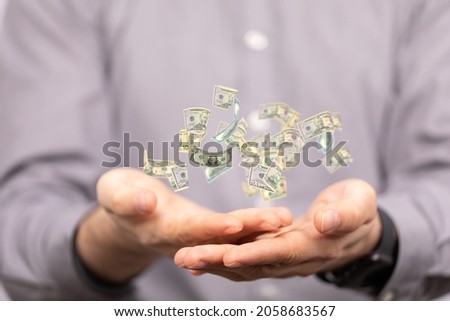 A rain of dollar banknotes falling in the hands of a person