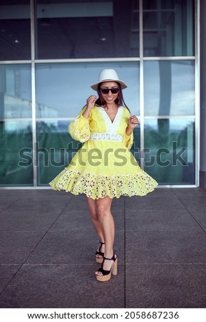 A pretty Hispanic woman in a yellow dress dancing in the street