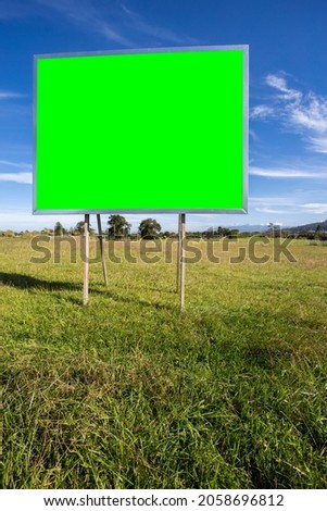 A metal poster on a green field on a sunny day. chroma key space for images or text. vertical image. advertisements