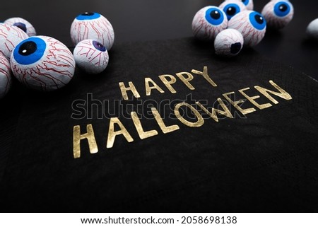 Funny Halloween treat - Candy eyeballs with a Napkin written "Happy Halloween" on dark background. Copy space