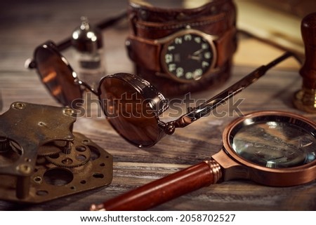 Steampunk still life - old vintage objecys on a wooden background. Leather wrist watch, dark glasses, aold tube lamps, magnifying glass, gears Royalty-Free Stock Photo #2058702527