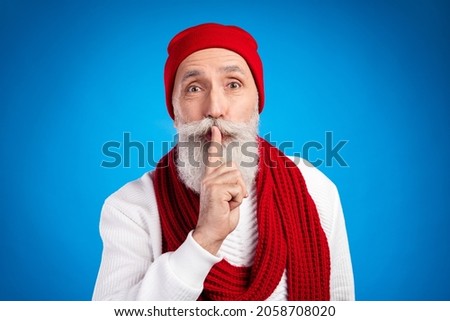 Photo of aged person finger covering lips do not talk look camera wear sweater isolated on blue color background