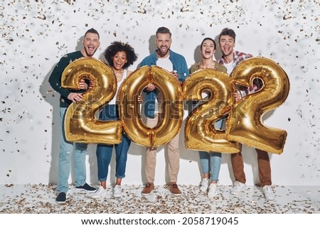Group of young beautiful people in casual clothing carrying gold colored numbers and smiling Royalty-Free Stock Photo #2058719045