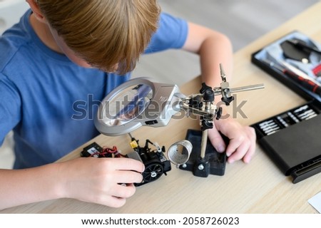 Top view table with Kid inventor assambling radio control robot Royalty-Free Stock Photo #2058726023