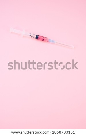 an isolated injection syringe on a pink background with text space