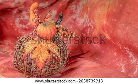 A harvest crft fprms a fall center piece on an orange background.