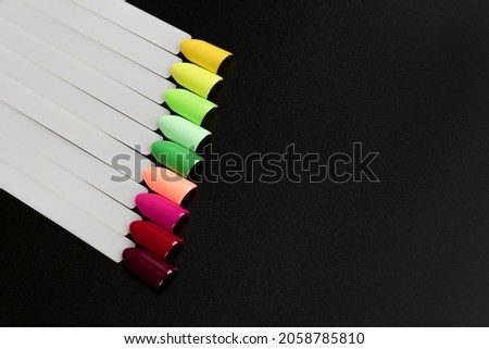Multiсolor nail tips on a black background. examples of manicure for nails. Palette with color samples of nail. Copy space