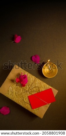 Diwali festive celebration gifts photo template with clear space for text. An elegant golden gift box arranged with Diwali lamp and flowers. View from above. Royalty-Free Stock Photo #2058801908